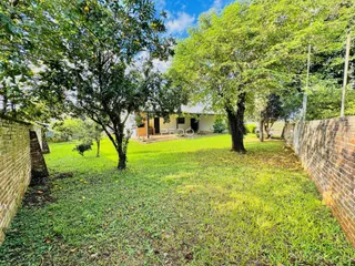 Vista externa de uma propriedade com jardim e árvores ao redor.