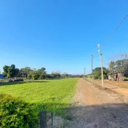 Vista de um campo aberto com vegetação e estrada de terra.