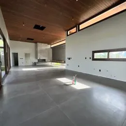 Ambiente interno amplo com teto inclinado e piso claro.