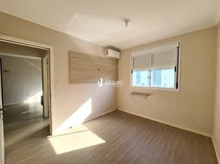 Interior de uma sala com piso de madeira clara e janela.