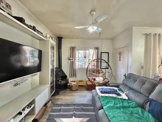 Imagem de uma sala de estar com sofá e televisão em uma residência.