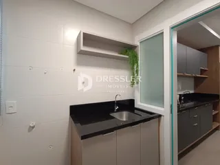 Vista interna de uma cozinha moderna com armários e bancada escura.