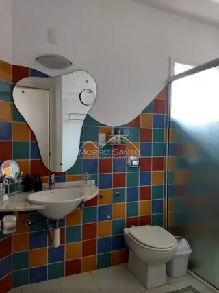 Banheiro com revestimento de azulejos coloridos e pia branca.