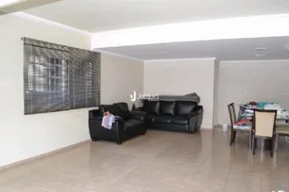 Sala de estar com móveis escuros e janela coberta por persianas.