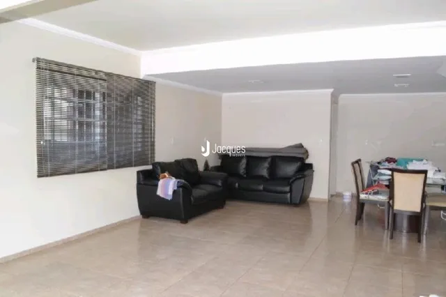 Sala de estar com móveis escuros e janela coberta por persianas.