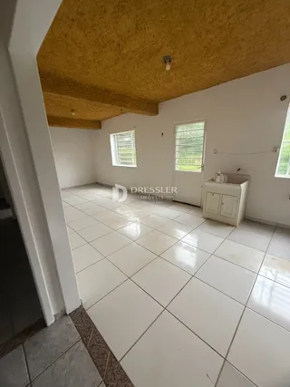Interior de uma sala com piso de cerâmica branca e teto texturizado.