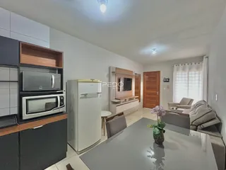 Sala de estar com cozinha integrada e mesa de jantar em um apartamento.