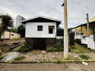 Fachada de uma residência em Lajeado, Brasil, com paredes brancas e telhado escuro.