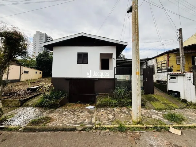 Fachada de uma residência em Lajeado, Brasil, com paredes brancas e telhado escuro.