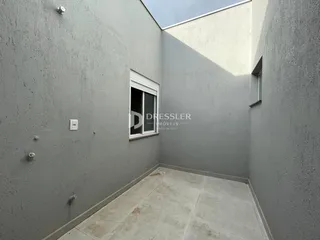 Vista de um corredor interno com paredes cinzas e piso de concreto.
