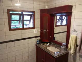 Foto do interior de um banheiro com revestimento de cerâmica e armário de madeira.