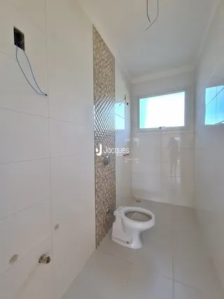 Foto de um banheiro interno com piso claro e azulejos brancos.