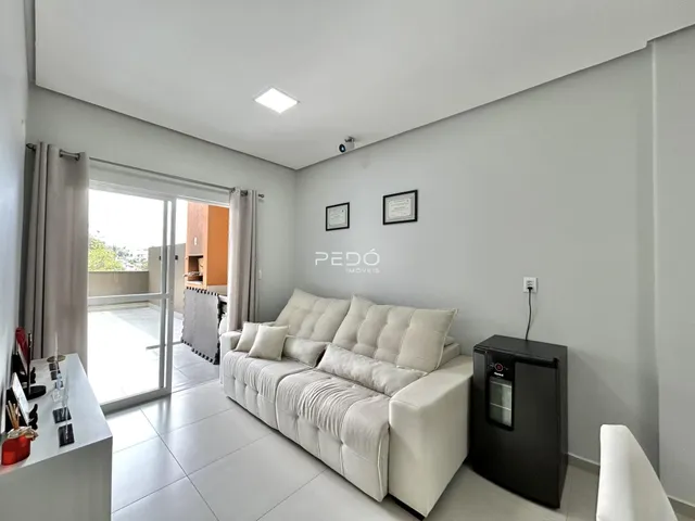 Sala de estar com sofá e porta de vidro de acesso ao exterior.