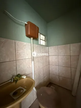 Foto interna de um banheiro com revestimento de azulejos claros e pia de cerâmica.