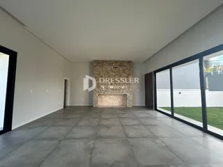 Interior de uma sala ampla com piso de concreto e parede de pedra no imóvel em Lajeado.