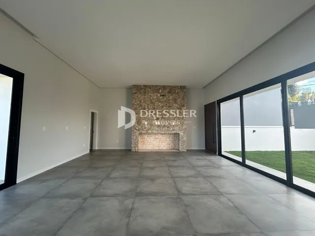 Interior de uma sala ampla com piso de concreto e parede de pedra no imóvel em Lajeado.