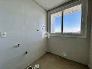 Vista de um canto de cômodo interno com paredes brancas e janela.