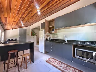 Cozinha moderna com armários cinzas e piso claro em um imóvel no Brasil.