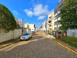 Vista externa de uma rua residencial com edifícios altos e pavimento de paralelepípedos.