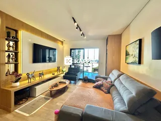 Sala de estar com sofá cinza e televisão na parede.