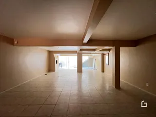 Corredor com piso de cerâmica e estrutura de teto exposta.