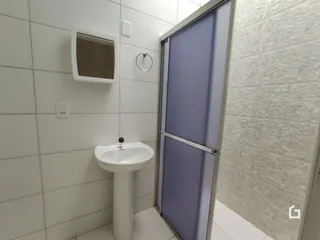 Banheiro com pia e espelho branco nas paredes brancas.