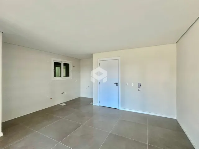 Ambiente interno de uma sala com paredes brancas e piso cinza.