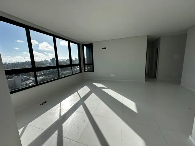 Ambiente interno com grande janela que oferece uma vista panorâmica da paisagem urbana.