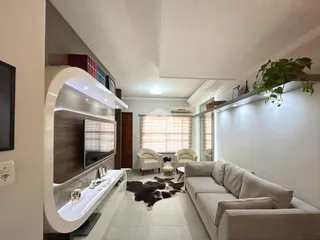 Sala de estar com sofá e televisão em um apartamento no Brasil.