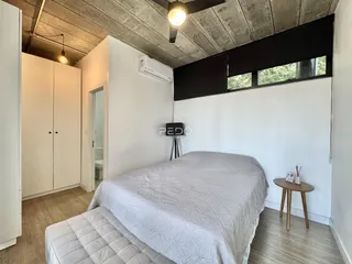 Quarto com cama e armários brancos em ambiente com teto de concreto.