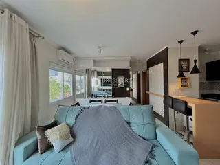 Sala de estar com sofá azul e cortinas brancas.