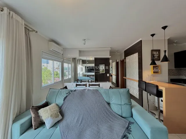 Sala de estar com sofá azul e cortinas brancas.