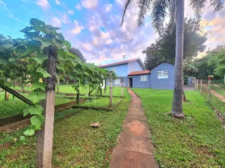 Vista externa de uma propriedade com jardim e cerca de madeira.