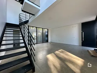 Interior de um espaço amplo com escadaria e grandes janelas.