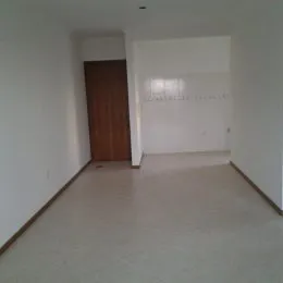 Hall de entrada com parede branca e porta de madeira.