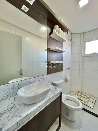 Foto de um banheiro com bancada de mármore e vaso sanitário branco.