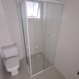 Foto de um banheiro com box de vidro transparente.