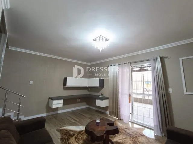 Sala de estar com piso de madeira e portas de vidro que dão acesso ao exterior.