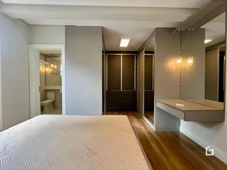 Quarto com piso de madeira e armários embutidos na parede.