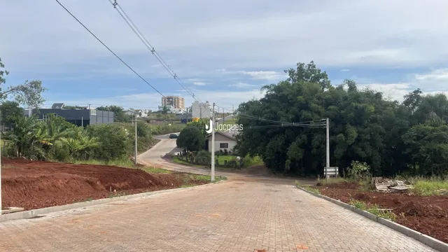 Vista da entrada de uma propriedade com terra e vegetação ao redor.