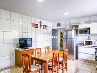 Uma sala de jantar com mesa de madeira e cadeiras é visível na foto.