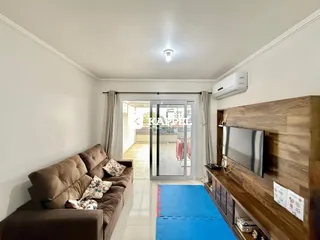 Sala de estar com sofá e painel de madeira, com porta de vidro para área externa.