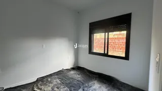 Quarto interno com parede branca e janela escura.