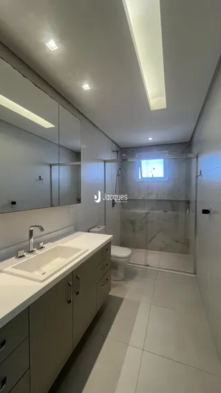 Banheiro moderno com box de vidro e bancada clara.
