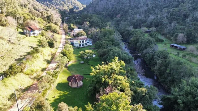 Vista aérea de uma propriedade em Lajeado, Brasil, mostrando a casa em meio a uma paisagem verde e rio.