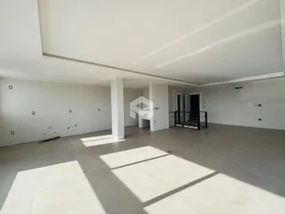 Interior de um espaço amplo com paredes brancas e piso claro.