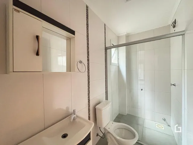 Foto de um banheiro com azulejos brancos e box de vidro.