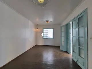 Ambiente interno de uma sala ampla com piso de madeira e portas de madeira azul-claro.