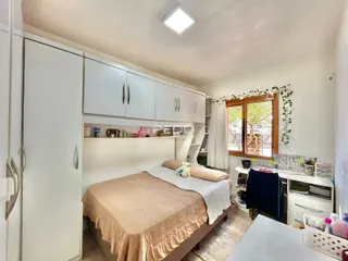 Quarto com armários brancos e janela de madeira.