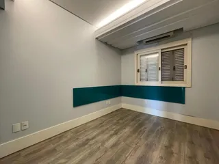 Uma sala de estar com piso de madeira clara e uma parede de destaque azul-petróleo.